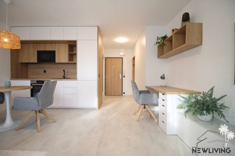 Interior of a 1-room apartment with a light floor featuring a wood design and practical furnishings.