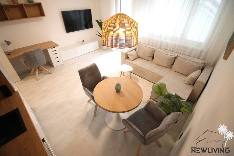 A one-bedroom apartment with a comfortable sofa, a desk, and a wooden decor floor.