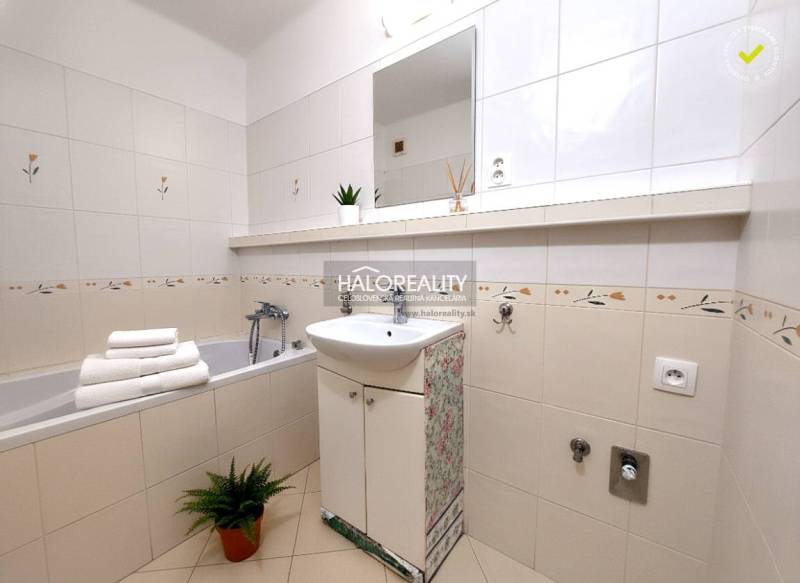 A bathroom with a bathtub and a sink in a 2-room apartment with decorative tiles.