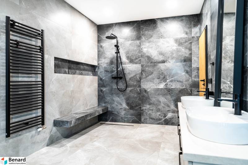 Modern bathroom with gray tiles, shower, and sinks in a family house.