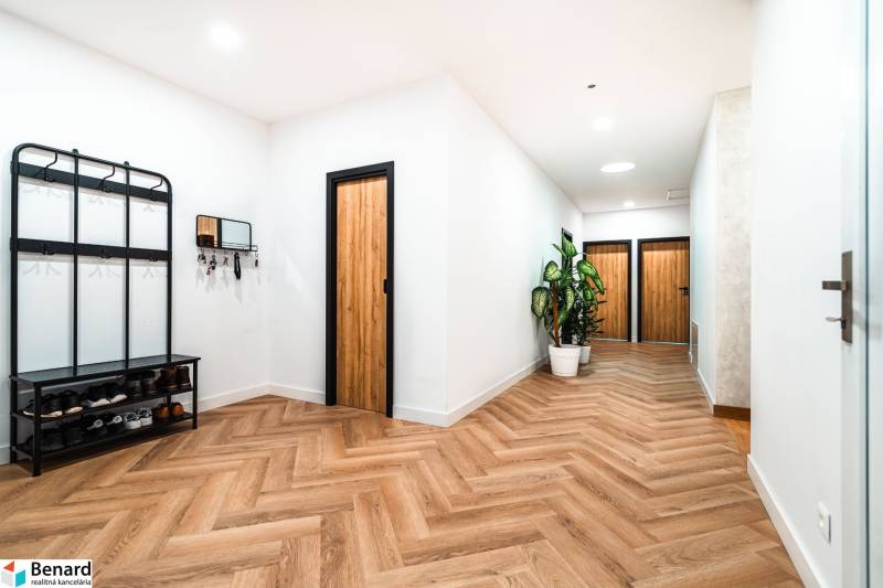 A hallway in a family house with a wooden decor floor, a shoe cabinet, and plants.