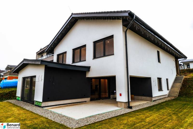 A family house in Stará Ľubovňa with a white facade, a terrace, and sloping terrain.