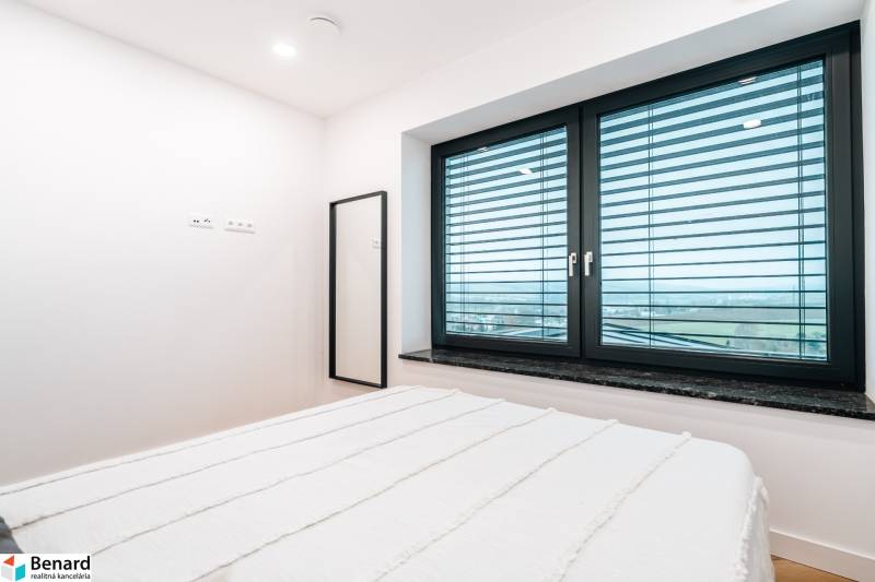 A bedroom in a family house with a large window and a mirror.