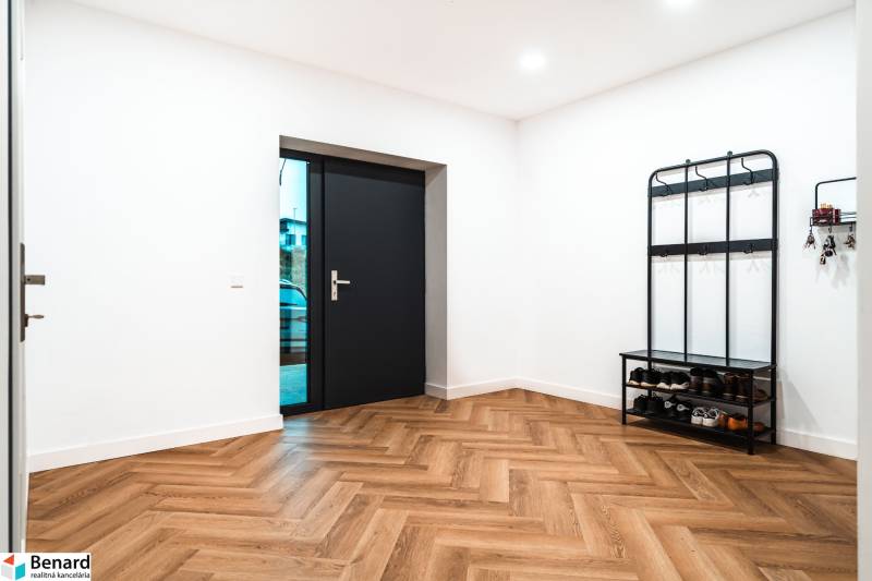 Entrance hall in a family house with a wooden decor floor, shoe rack, and coat hooks.