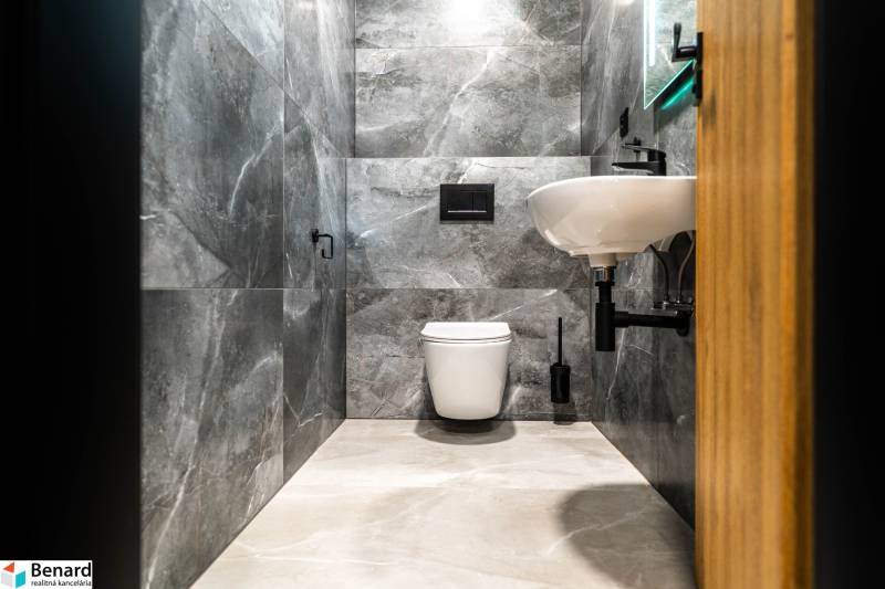 A bathroom in a family house with marble walls and white sanitary fixtures.