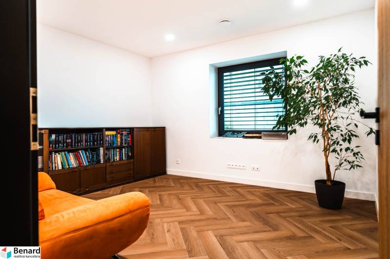 A room in a family house with a comfortable armchair, a bookshelf, and a wooden decor floor.