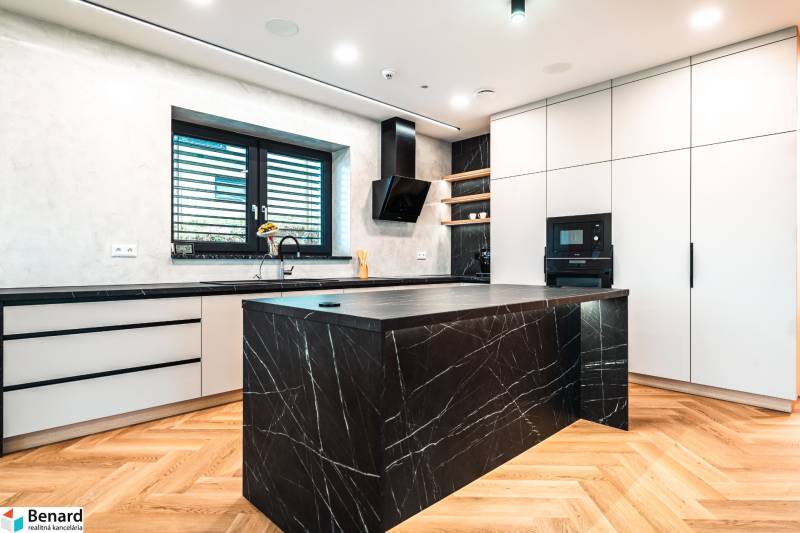 A kitchen in a family house with a marble island and a wood-patterned floor.