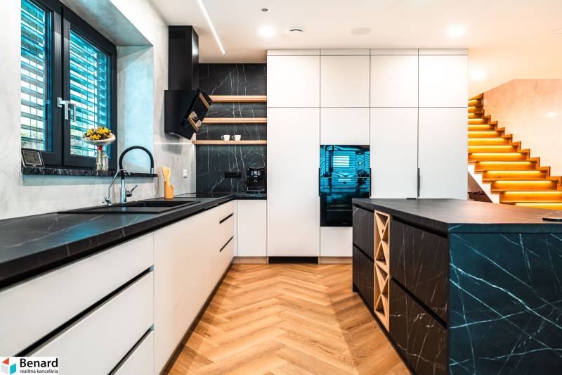 A kitchen in a family house with a wooden decor floor and black countertops.