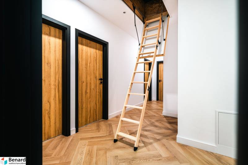 A wooden decor floor in the hallway of a family house with a pull-out staircase.