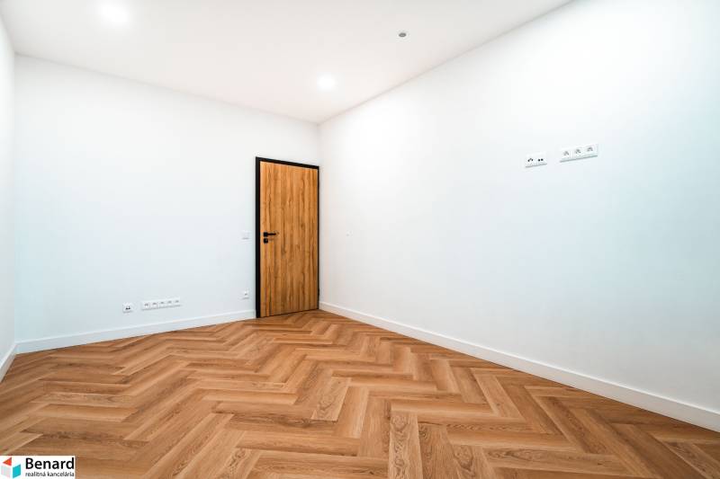 A spacious room in a family house with a wooden decor floor and distinctive wooden doors.