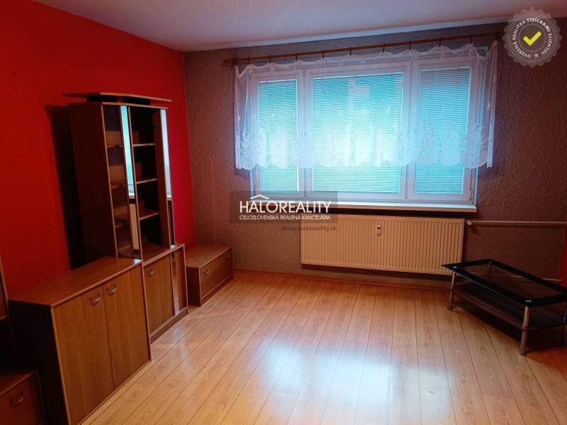A room with a wooden decor floor, red walls, and furniture in a 3-room apartment.