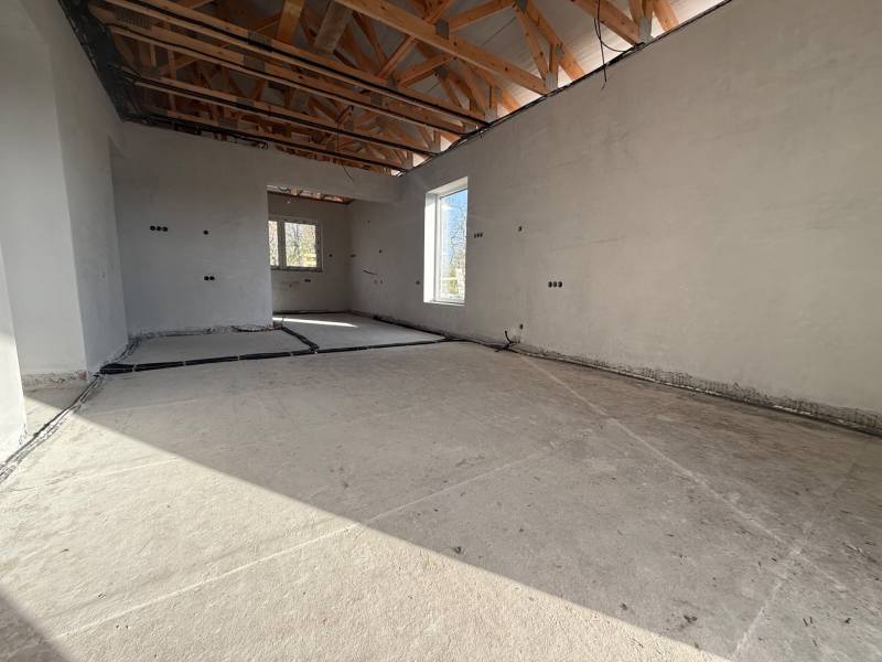 Interior of a family house with a concrete floor, wooden beams, and electrical wiring.