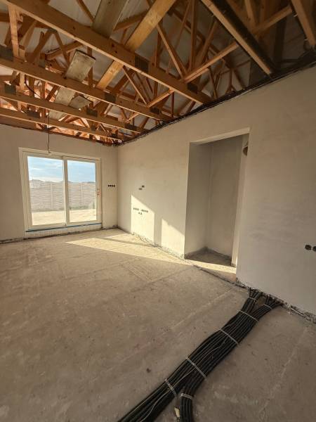 The interior of a family house with exposed ceiling beams and electrical installation preparation.