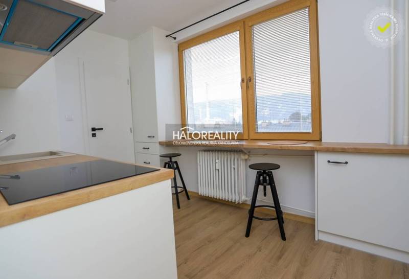 A kitchen in a 2-room apartment with white cabinets and a wood-patterned floor.