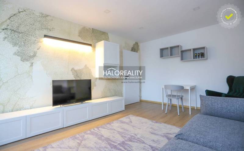 Living room in a two-room apartment with a wood-patterned floor and a television.
