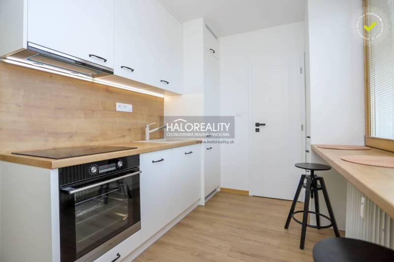 The kitchen of a two-room apartment, a floor with a wooden decor, a bright room with a large window.