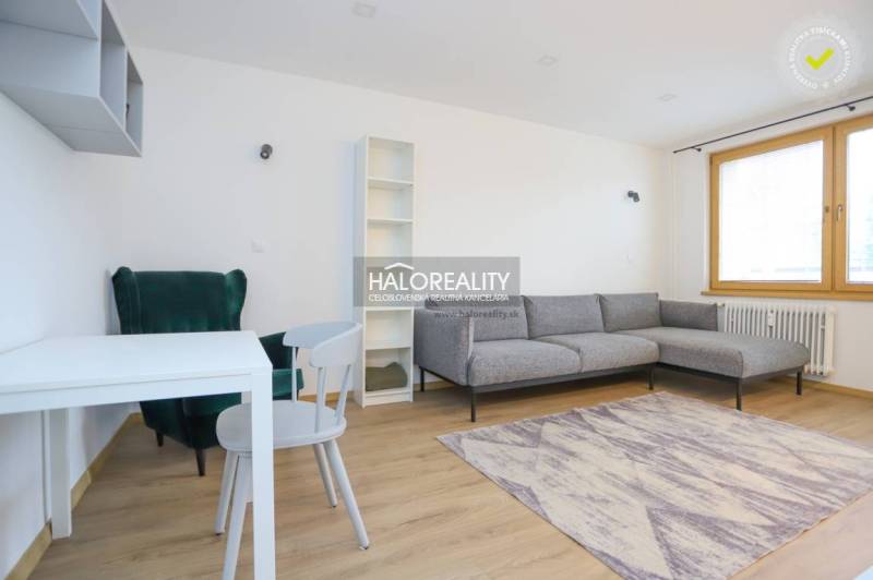 Living room in a two-room apartment with a sofa, table, armchair, and floor with a wooden decor.