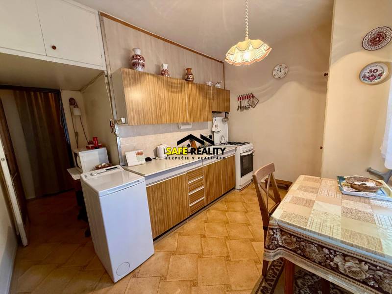 A kitchen in a 2-room apartment with a wooden kitchen unit and a dining table.