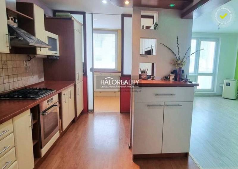 A kitchen in a studio apartment with a wood-patterned floor and a light interior.