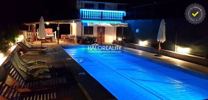 A nighttime atmosphere at the cottage in Byšte with an illuminated pool and seating on the terrace.