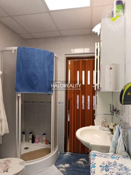 A bathroom with a shower in the cottage, equipped with a sink and storage cabinets.