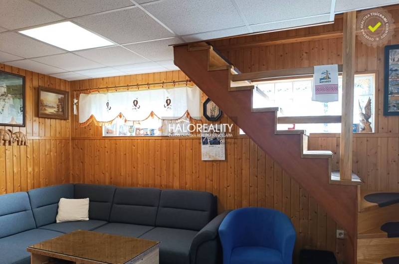 Interior of a cabin with wooden paneling, stairs, a sofa, and decorations on the walls.