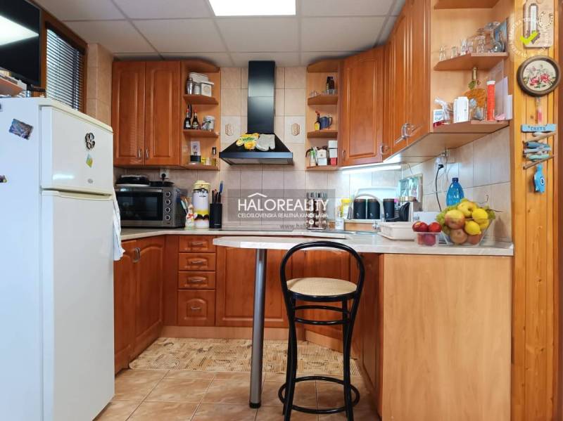 A kitchen in a cabin with wooden decor, a bar counter, and appliances.