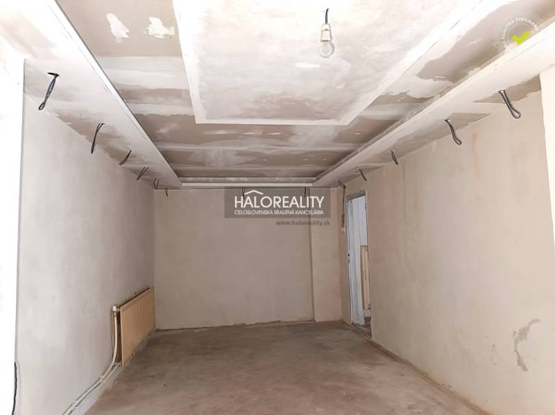 An unfinished room in a family house with white walls and a brick floor.