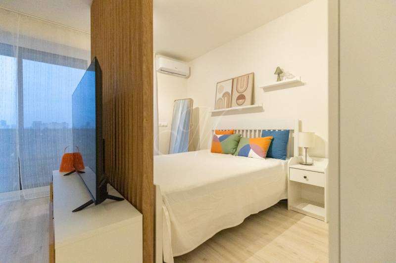 1-bedroom apartment with a bed, television, and decorative pillows. Floor with wooden decor.