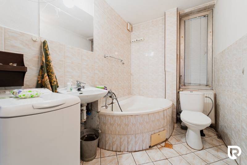 Bathroom with a bathtub, sink, and washing machine in a family house.