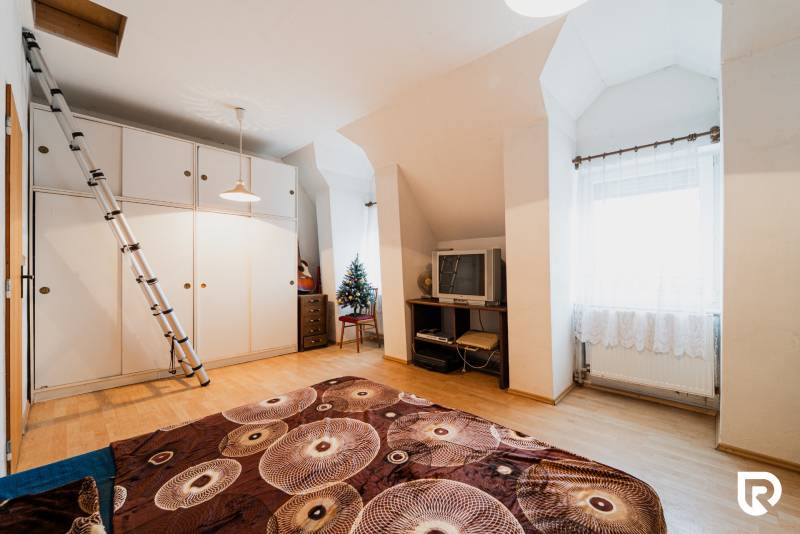 A room in a family house with a wooden decor floor, a television, and a wardrobe.