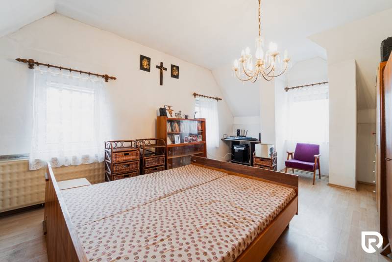 Bedroom in a family house with wood-patterned flooring, a bed, and a workspace.