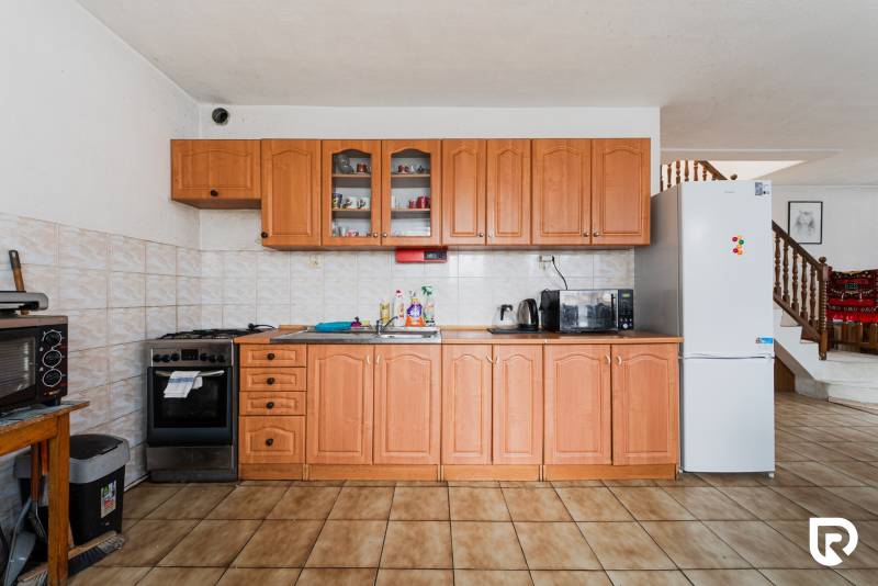 A kitchen in a family house with wooden cabinets, a white refrigerator, and wooden decor flooring.
