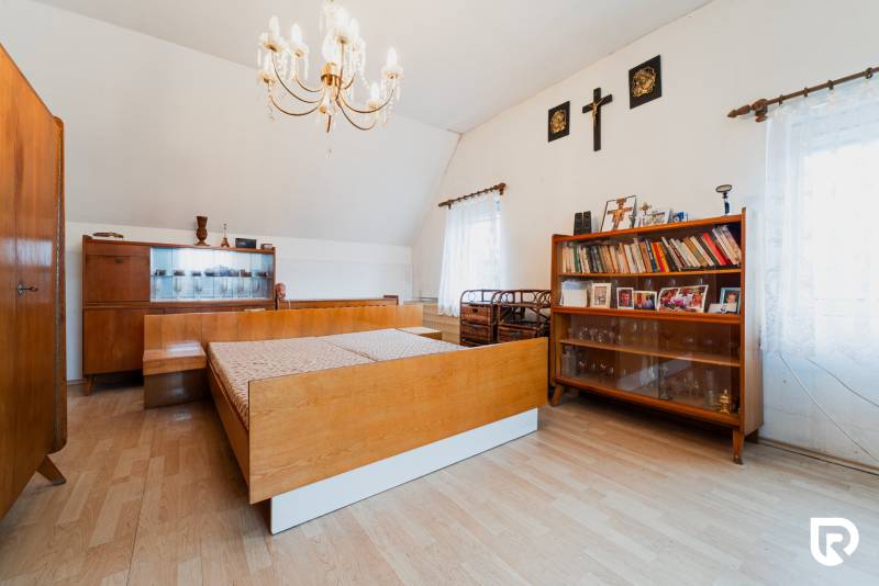 Bedroom in a family house with wood-decor flooring, a bookshelf, and a chandelier.