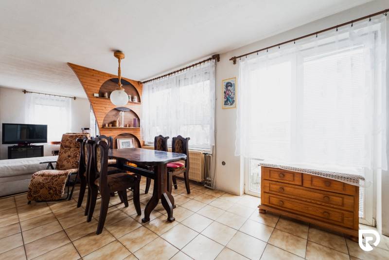 Dining area in a family house with wooden decor on furniture and shelves.