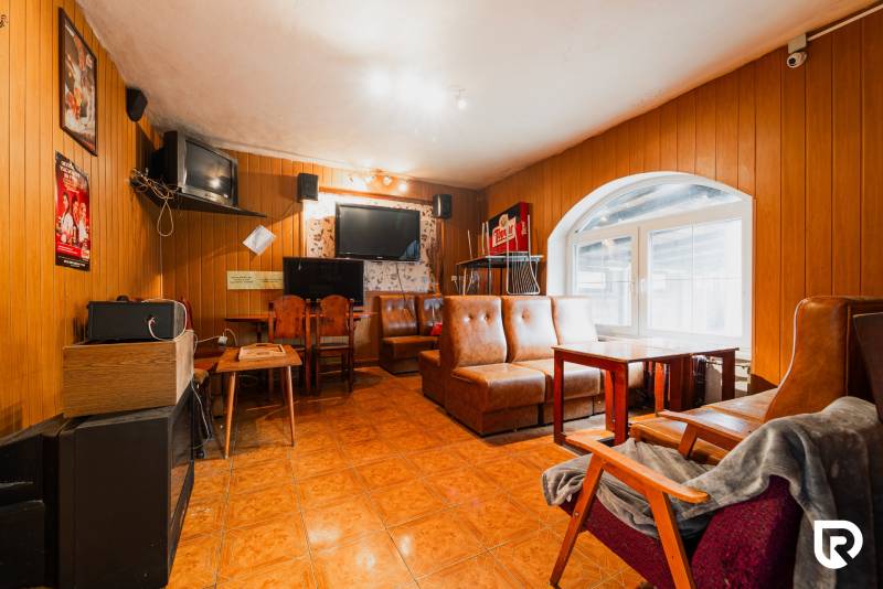 Interior of a family house with leather sofas, wooden paneling, and televisions.