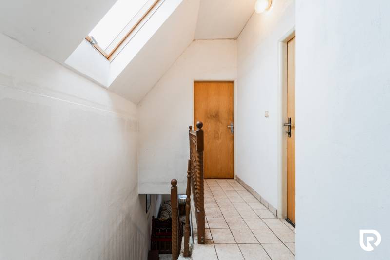 A hallway with a skylight and light walls in a family house, wooden railing, cladding.
