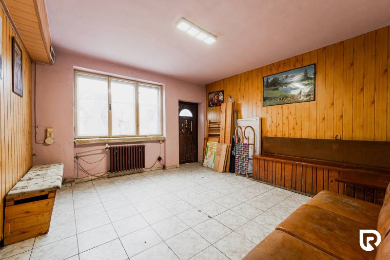 Interior of a family house with tiling, wooden paneling, and a sofa by the window.