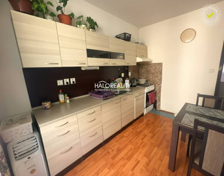 A kitchen in a 3-room apartment with a wooden decor floor, light cabinets, and a dining table.