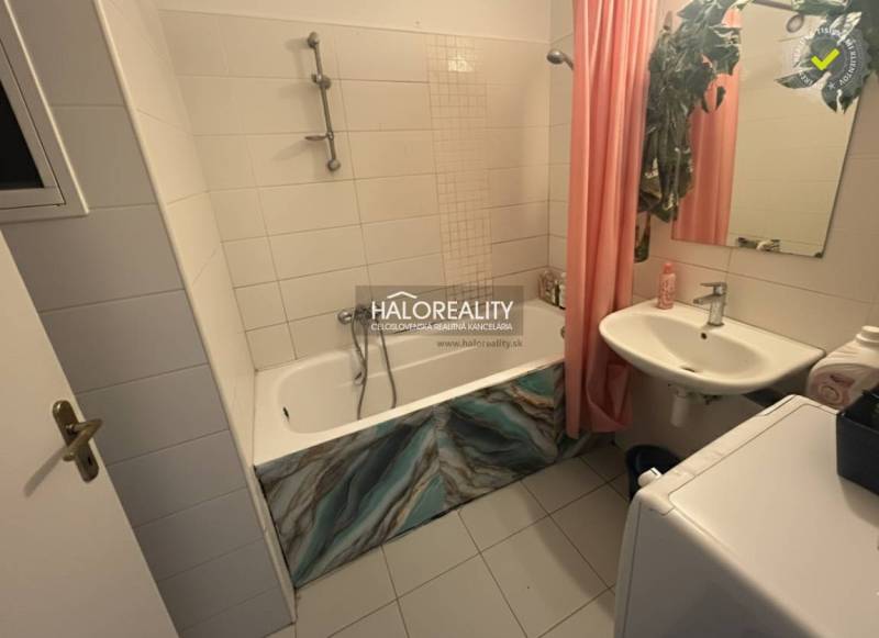 Bathroom with a bathtub, sink, and washing machine in a 3-room apartment, tiled with white tiles.
