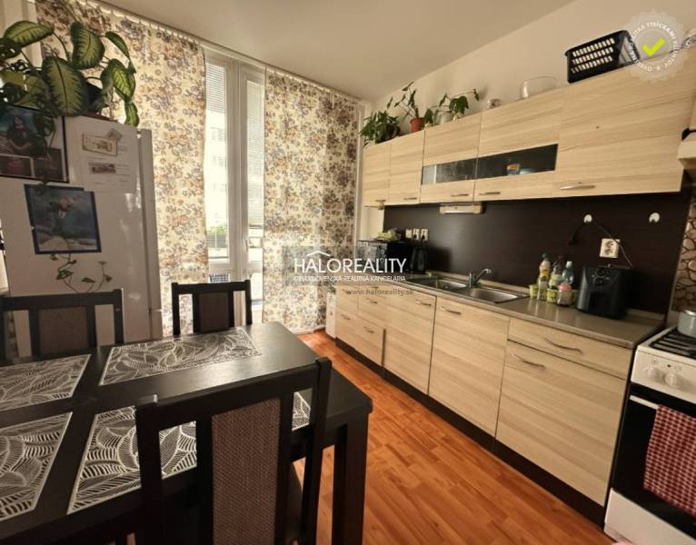 The kitchen in a 3-room apartment with a wooden decor floor, a dining table, and curtains.