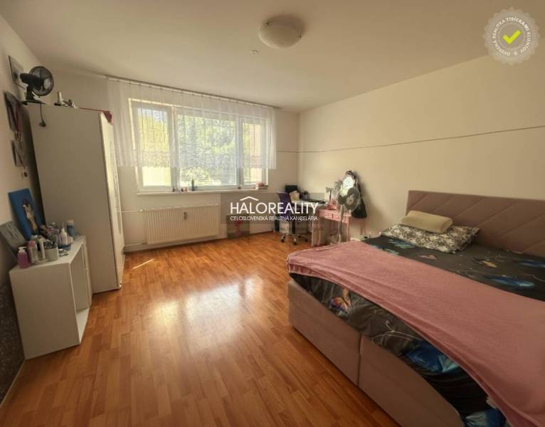 A bedroom in a 3-room apartment with a wood-patterned floor and a large window.