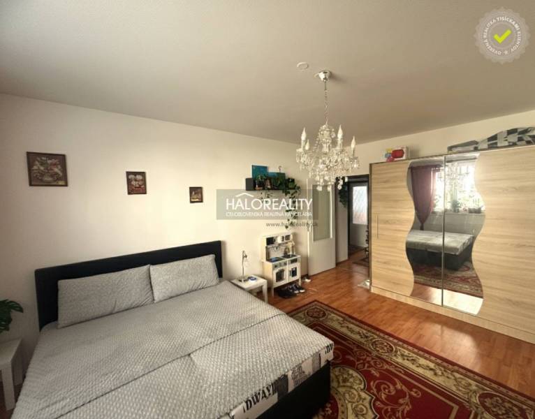 A bedroom with a chandelier and a wardrobe, a floor with a wooden decor in a 3-room apartment.