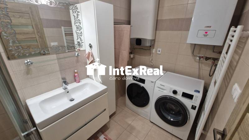 A bathroom with a sink, washing machine, and dryer in a 3-room apartment.