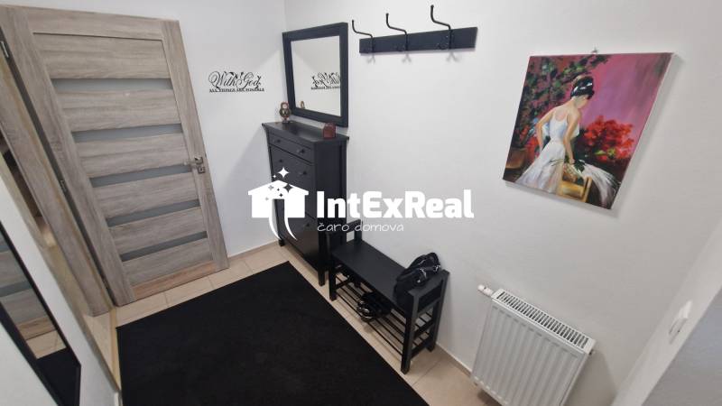A hallway in a 3-room apartment with a painting, a cabinet, and a coat rack.