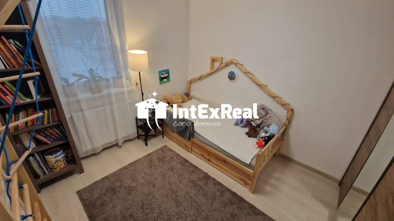 Children's room in a 3-room apartment with a light floor and a shelf full of books.