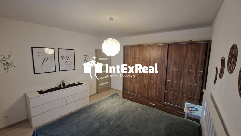Bedroom in a 3-room apartment with wood-patterned flooring, white furniture, wall decorations.