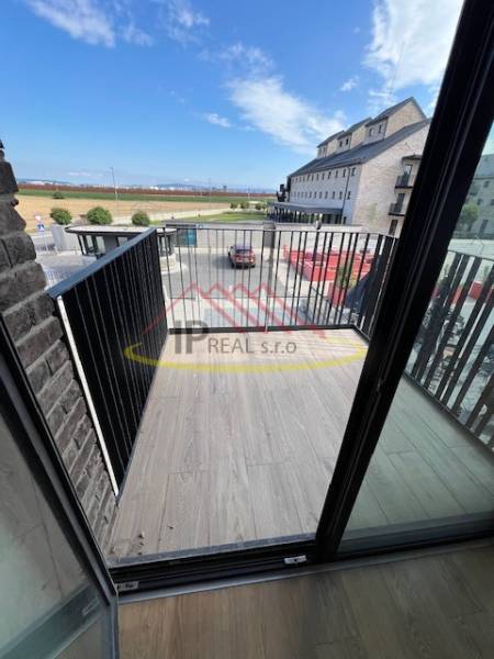 A balcony with a wooden decor floor in a 2-room apartment with a view of the surroundings.