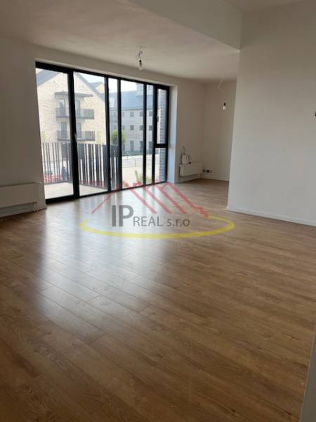 Living room with wood-patterned flooring in a two-room apartment, glass doors to the balcony.
