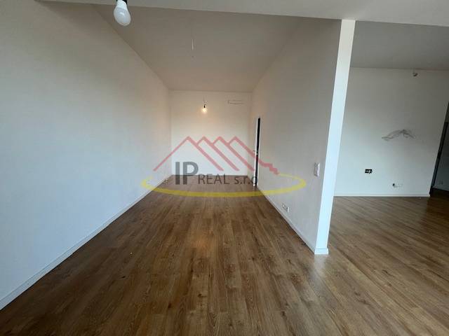 A room with a wooden decor floor in a 2-room apartment, neutral walls.